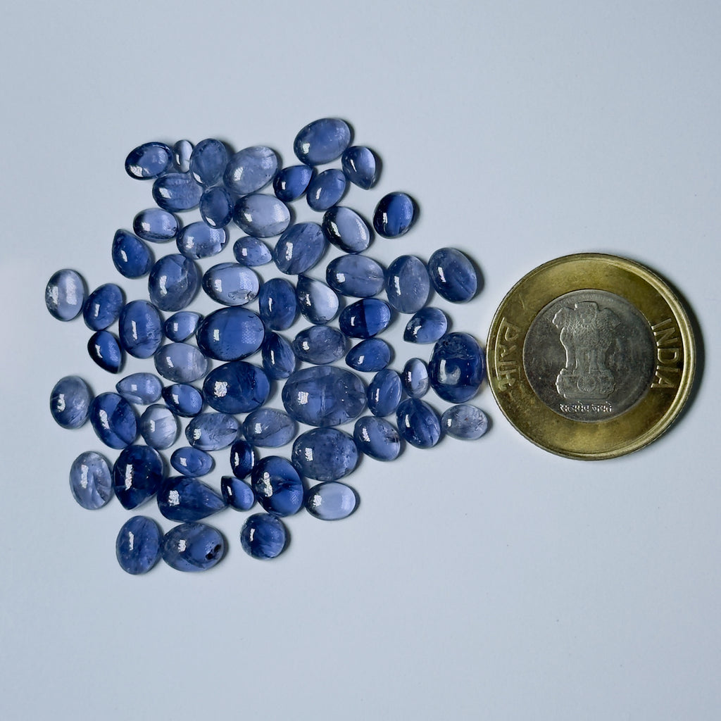 Blue gemstones with a coin for scale on a light gray background