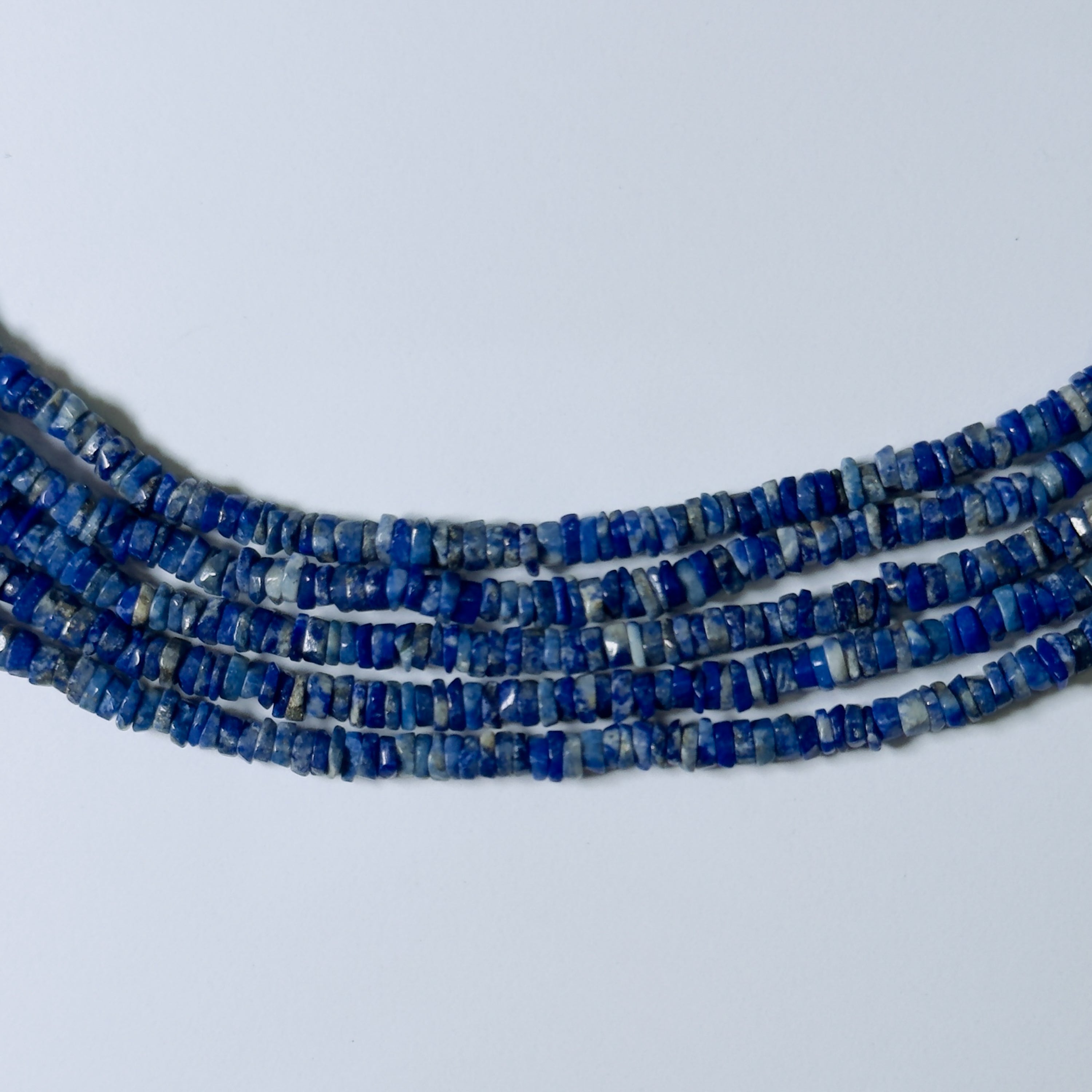 Three strands of blue beads on a light gray background