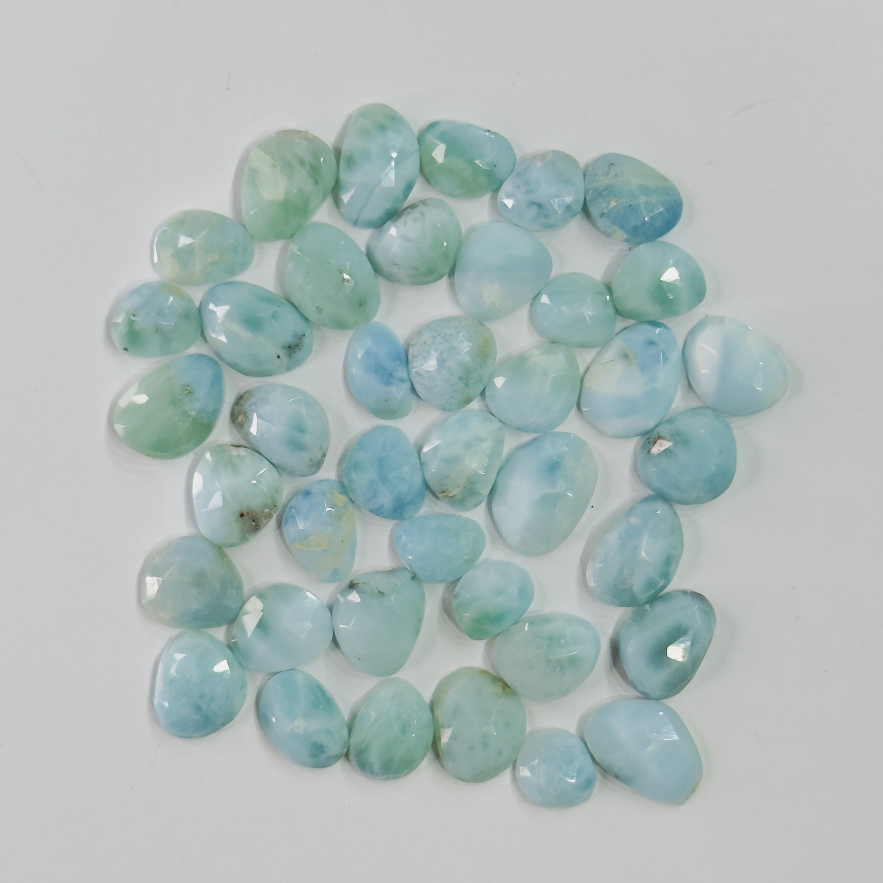 Collection of light blue and green stones on a white background