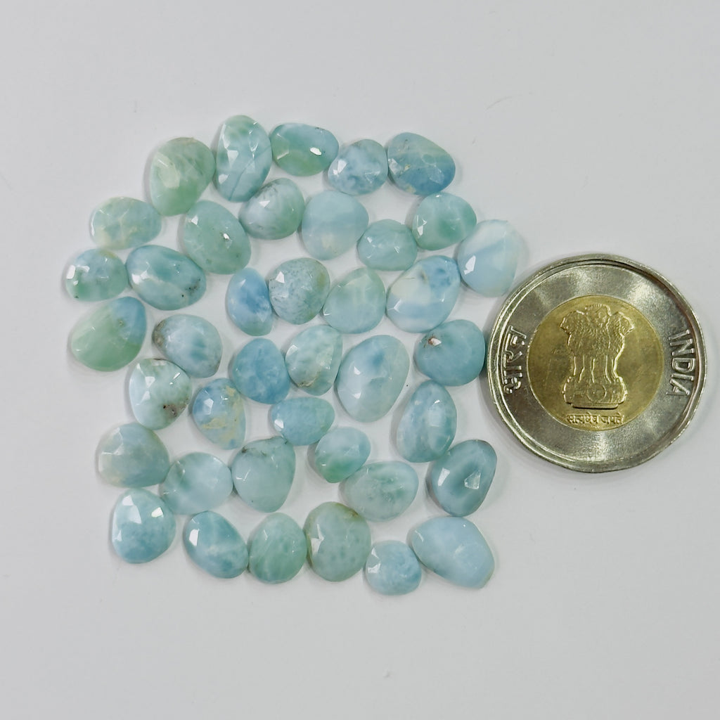 Turquoise-colored stones with a coin for scale on a white background