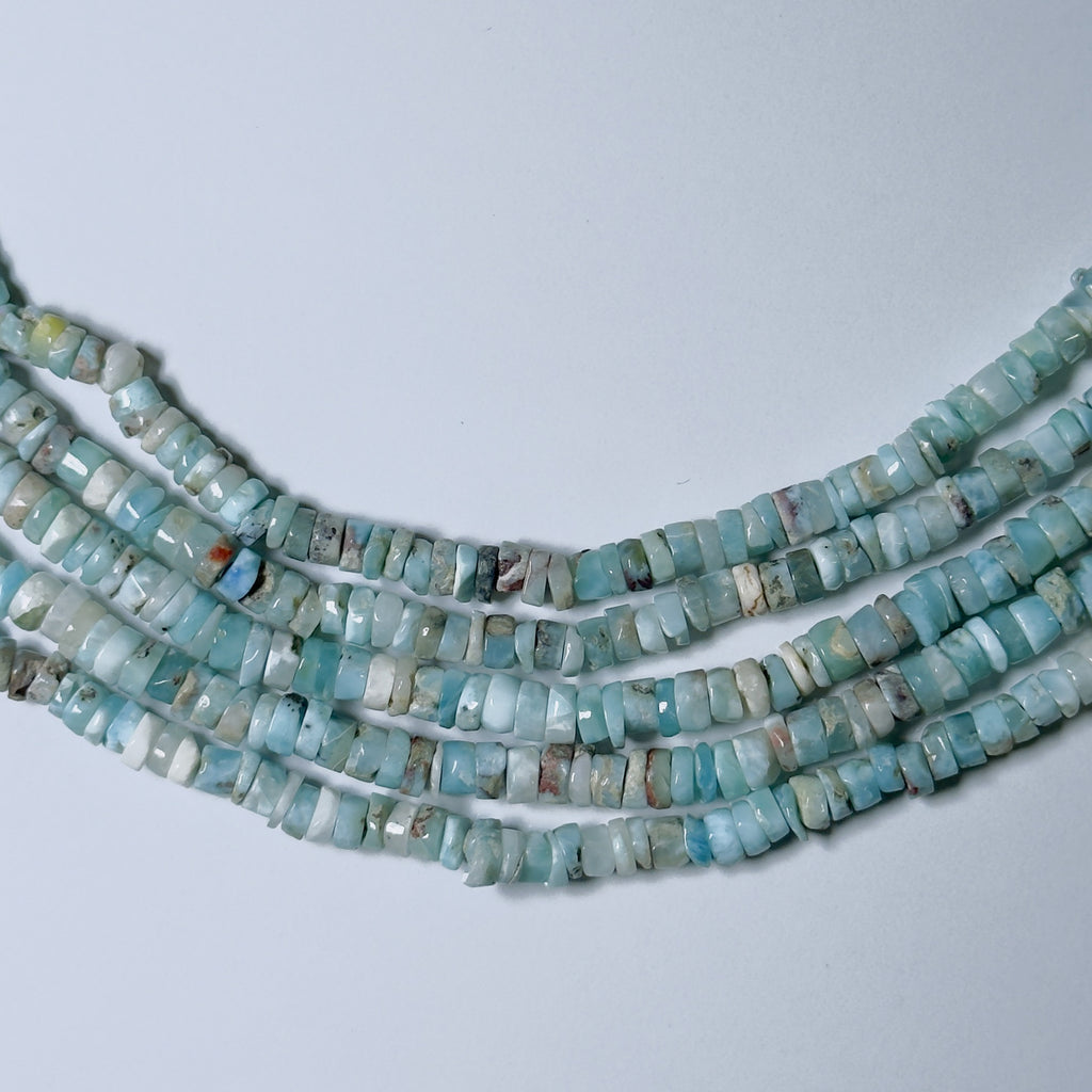 Strands of turquoise beads on a light gray background