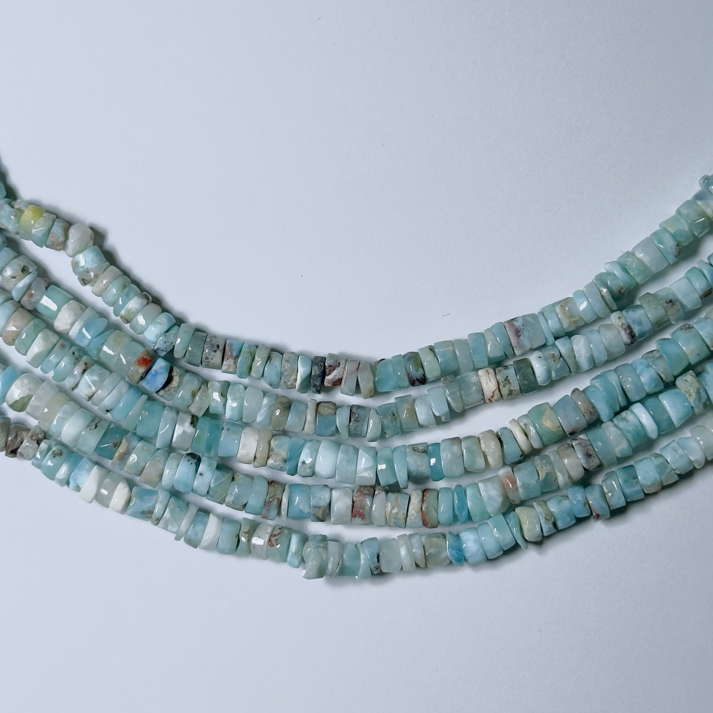 Strands of turquoise beads on a light gray background