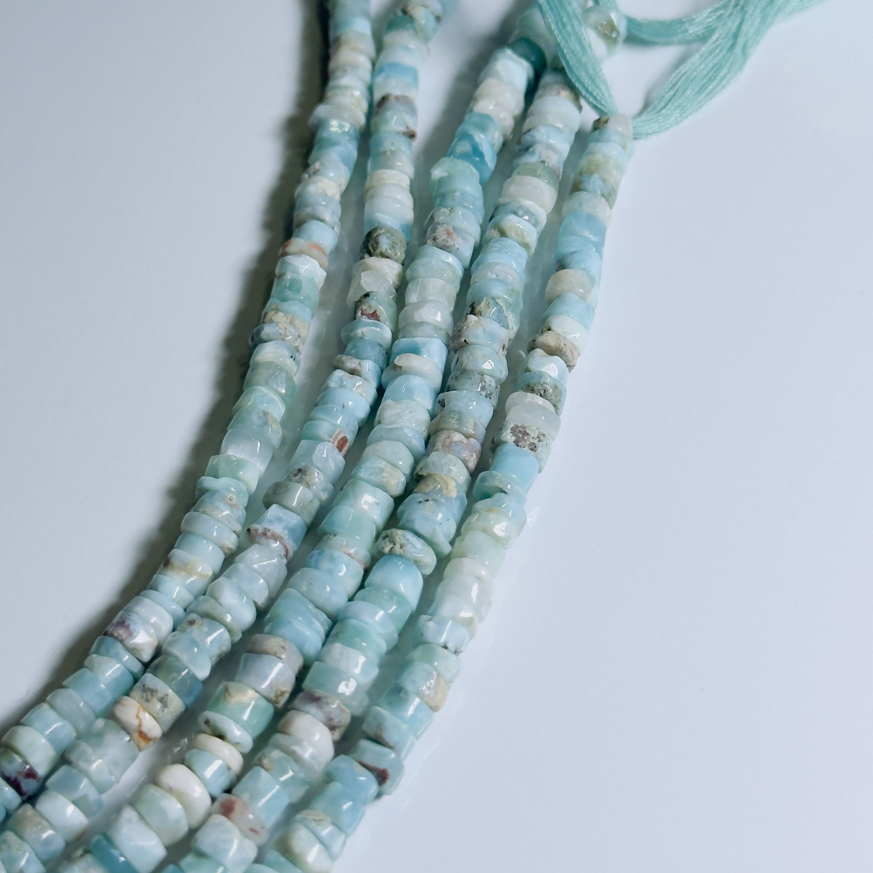 String of light blue beads on a white background
