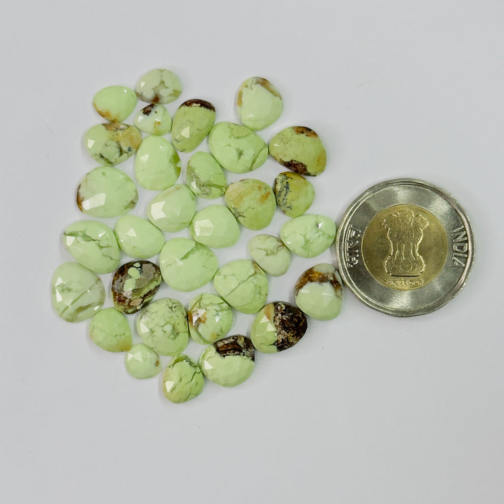 Green gemstones with a coin for scale on a light gray background