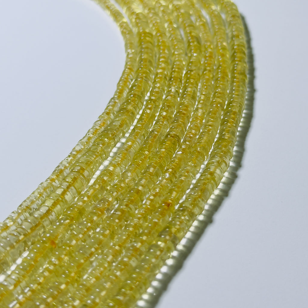 Close-up of a string of small yellow beads on a light gray background