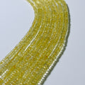 Close-up of a string of small yellow beads on a light gray background