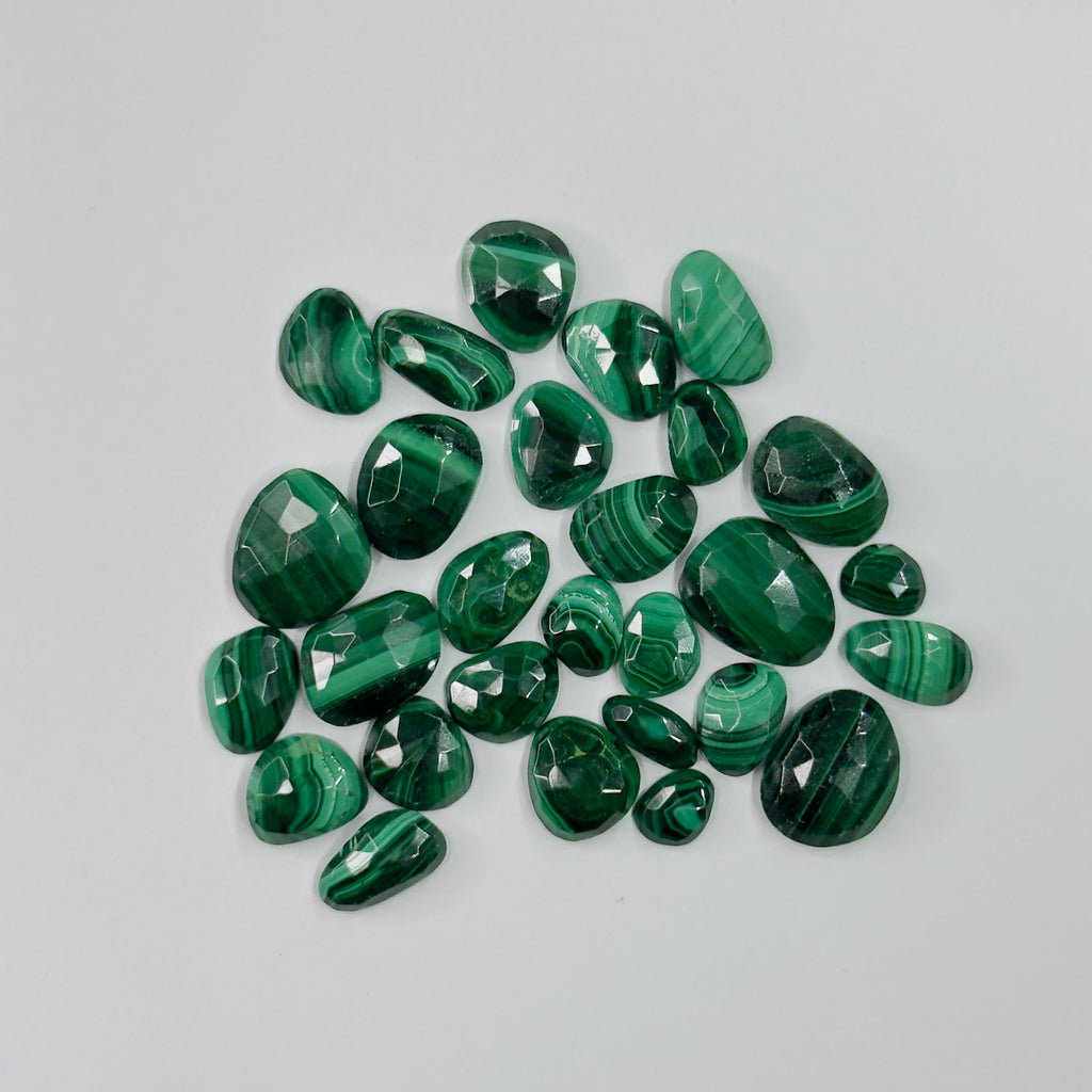 Collection of green gemstones on a light gray background
