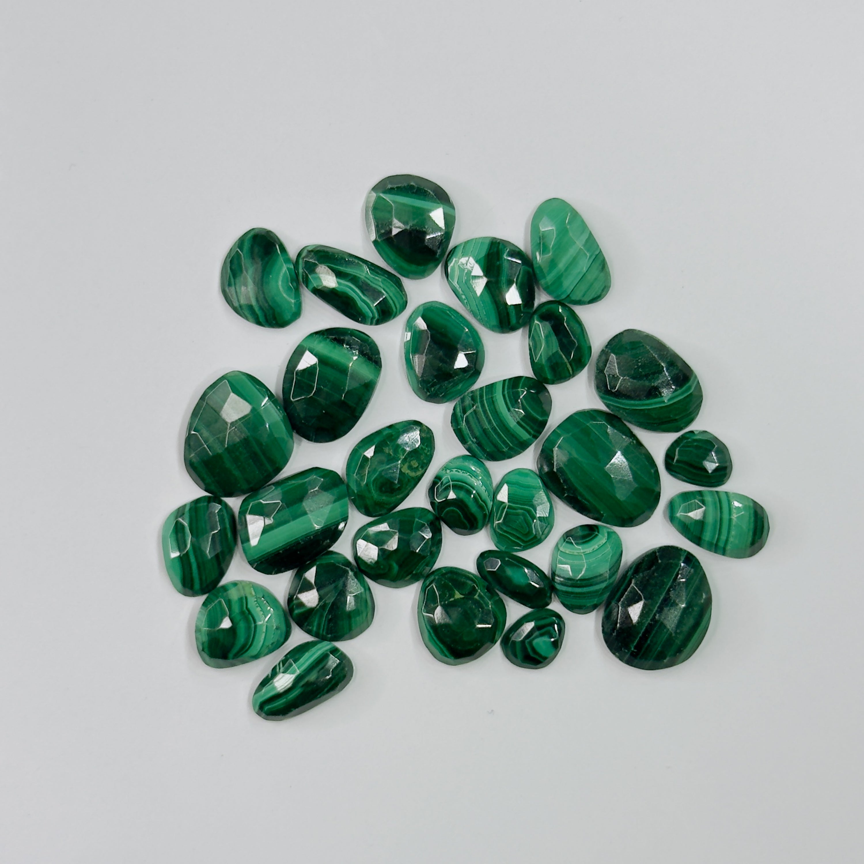 Collection of green gemstones on a light gray background
