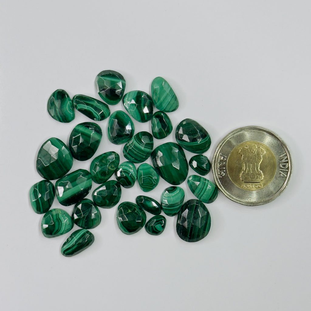 Green gemstones on a gray background with a coin for scale.