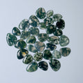 Collection of green and black marbled stones on a light gray background