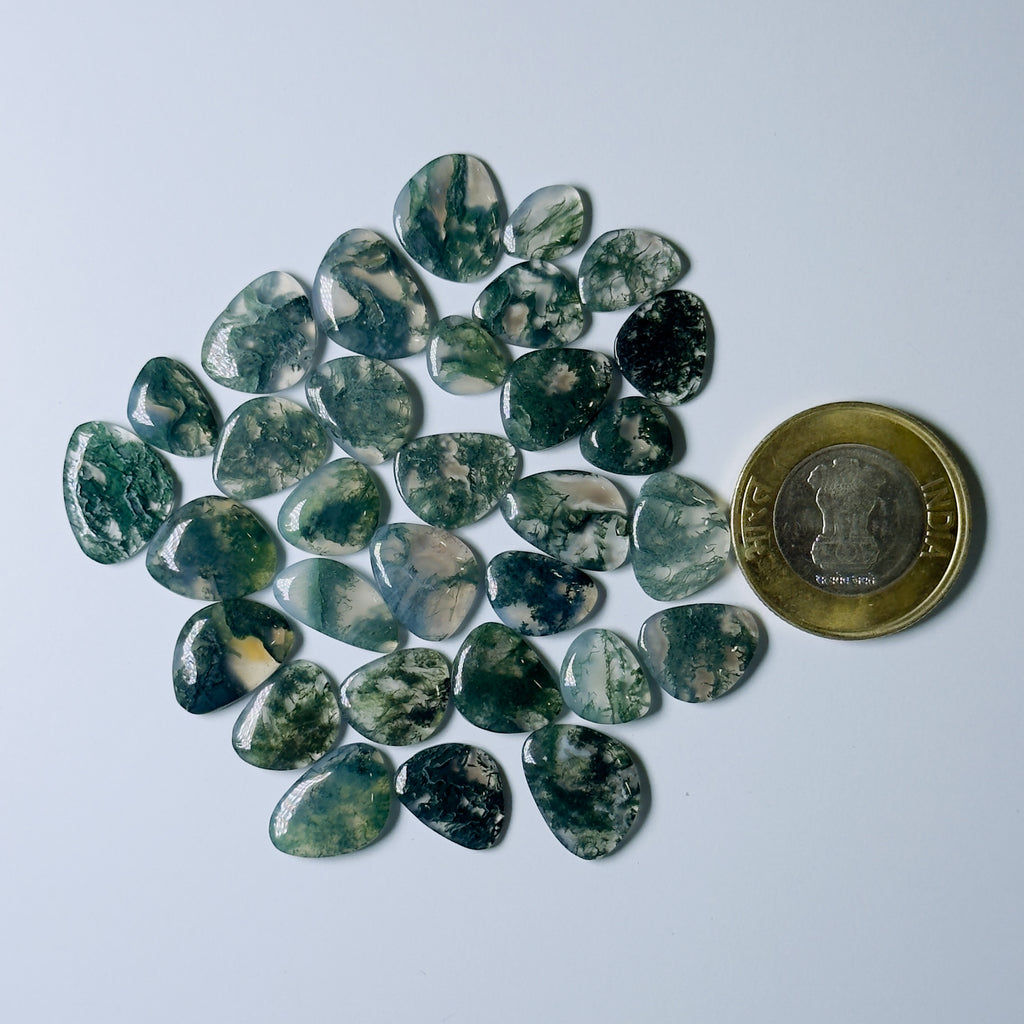 Green and black marbled stones with a coin for scale on a light gray background
