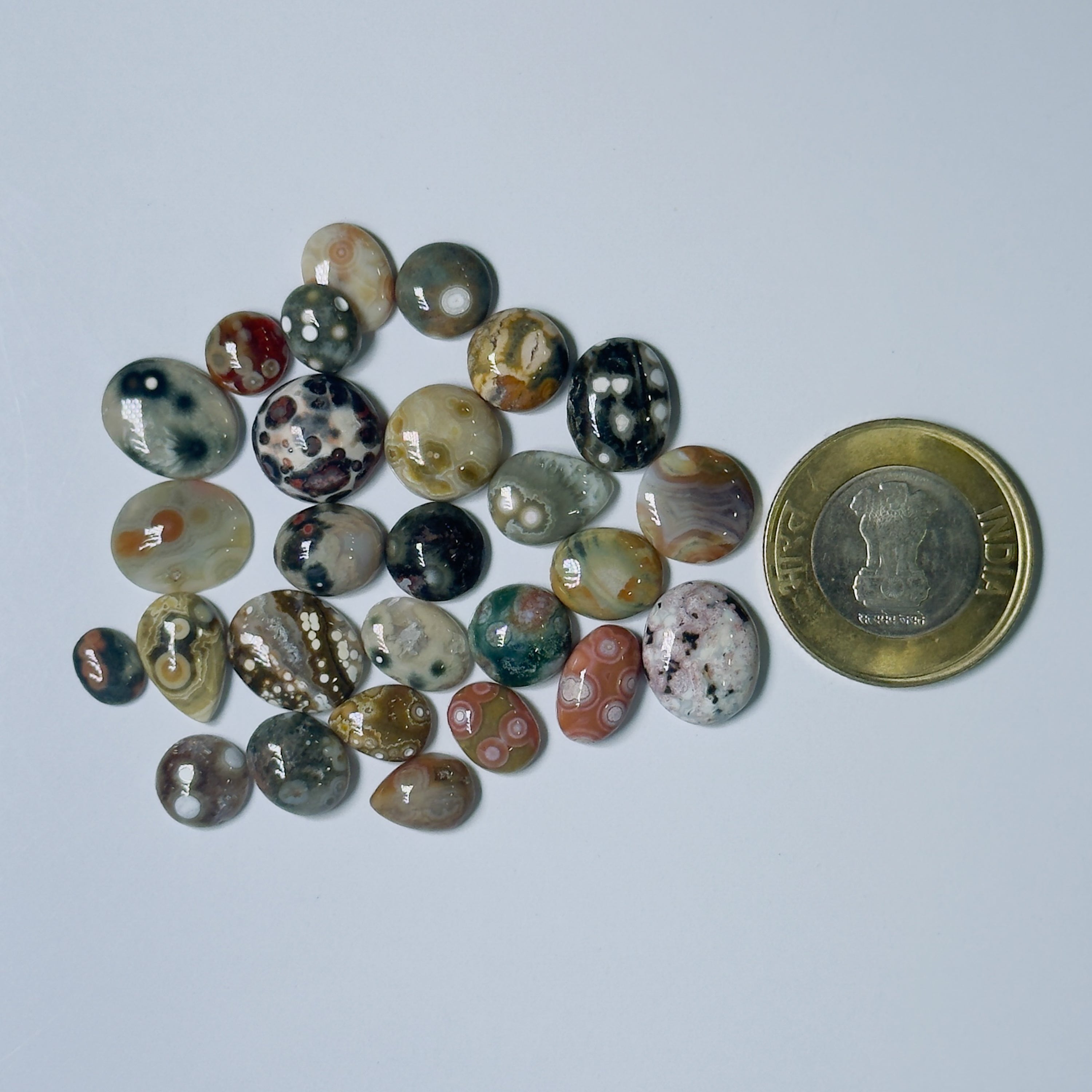 Collection of multicolored stones with a coin for scale on a light gray background