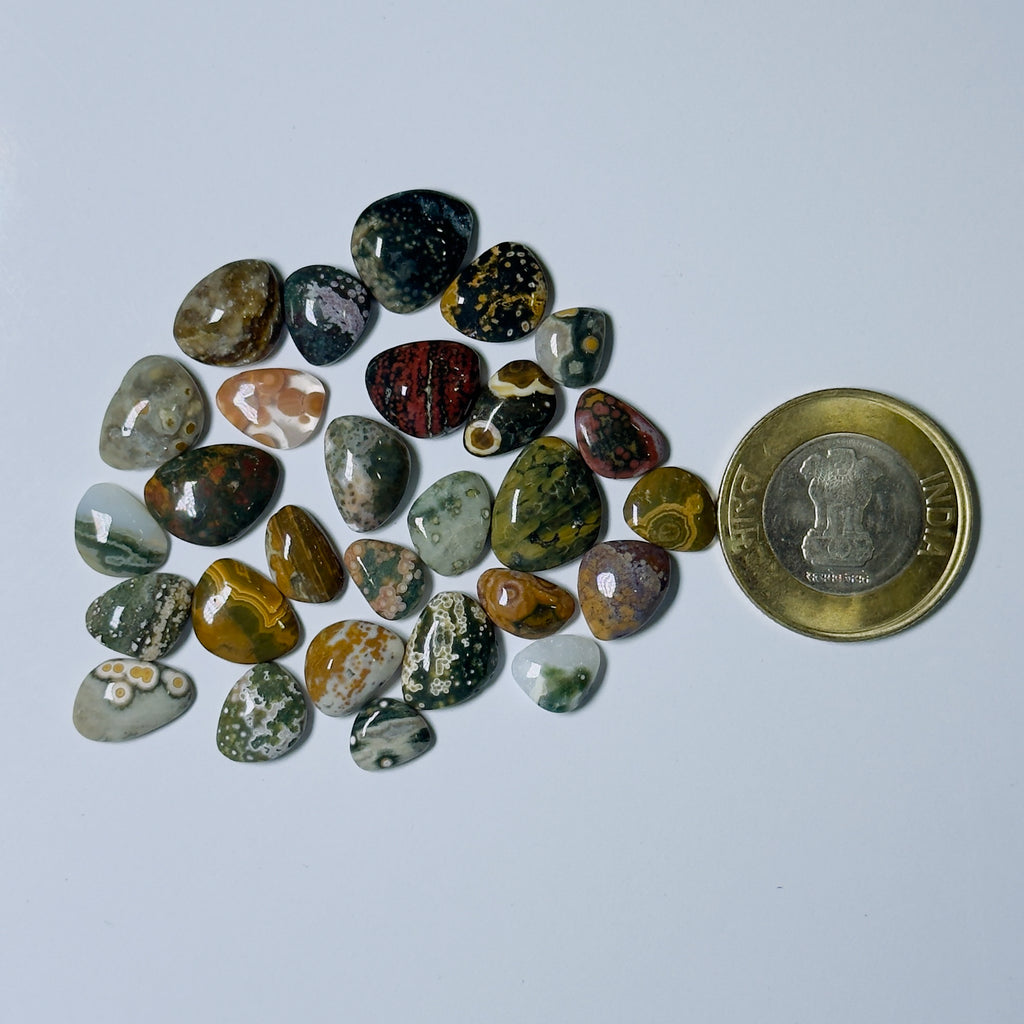 Collection of multicolored stones on a white background with a coin for scale.