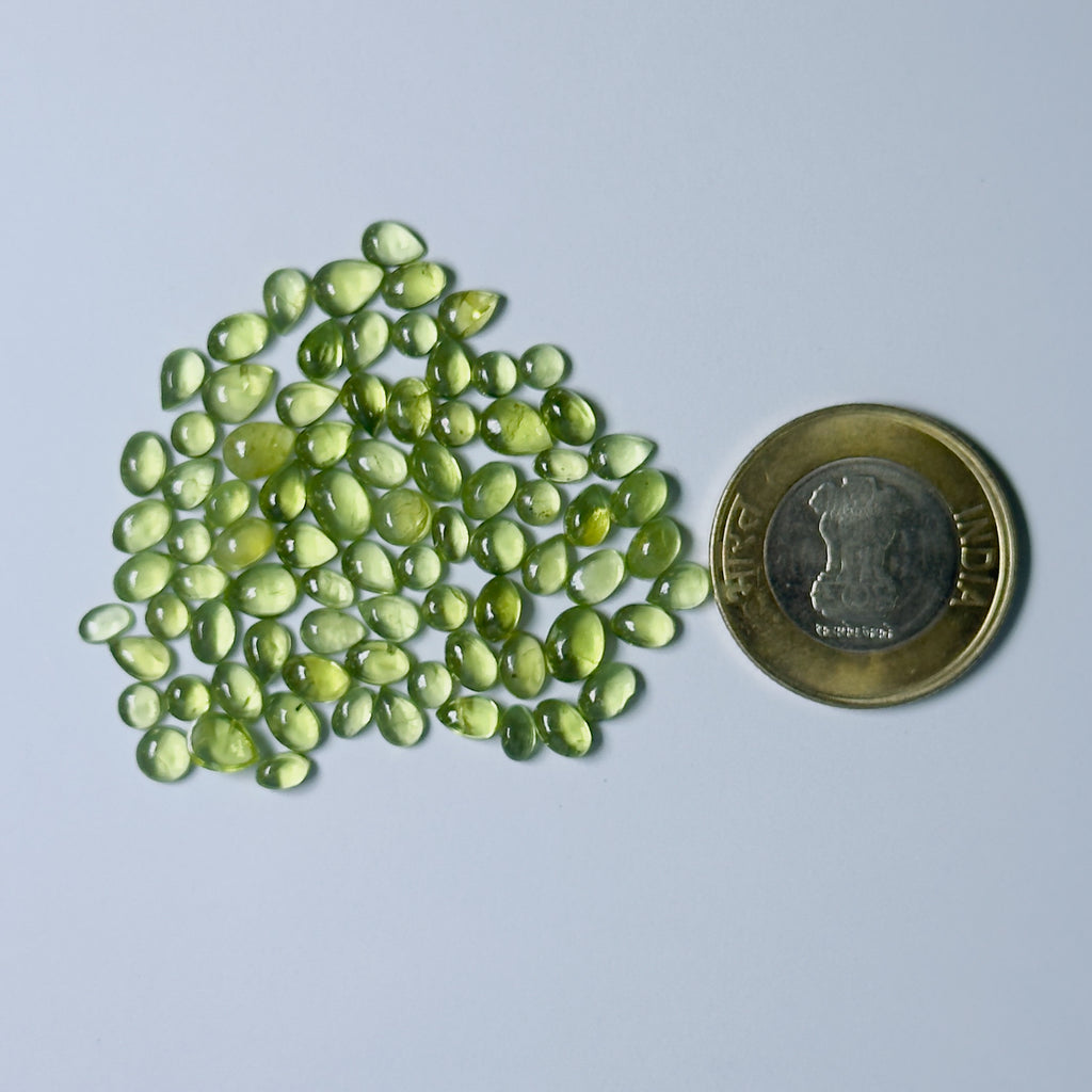 Green gemstones with a coin for scale on a White background
