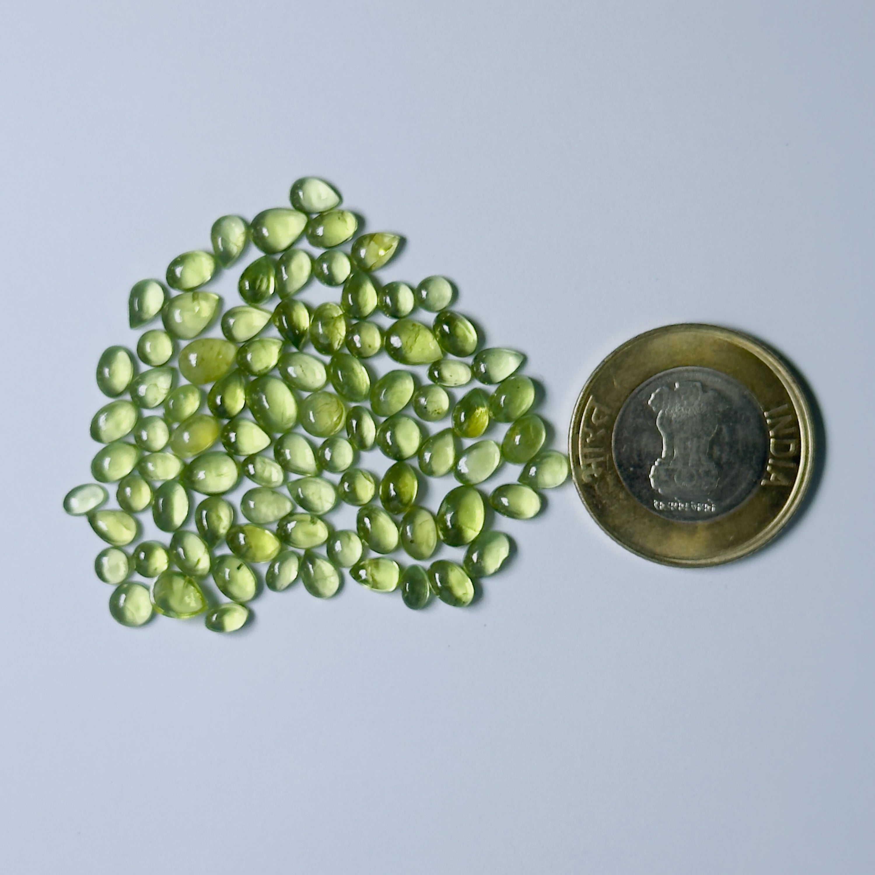 Green gemstones with a coin for scale on a White background