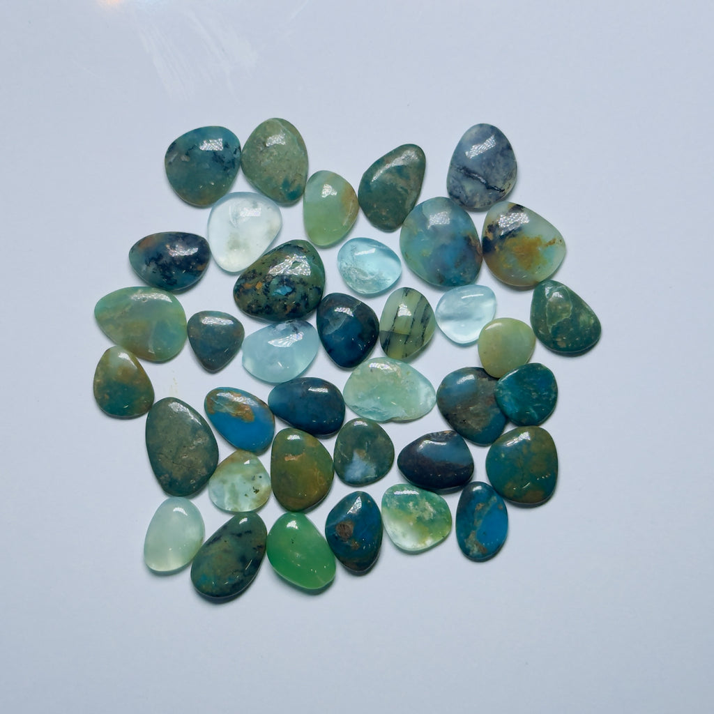 Collection of green and blue stones on a light gray background