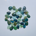 Collection of green and blue stones on a light gray background