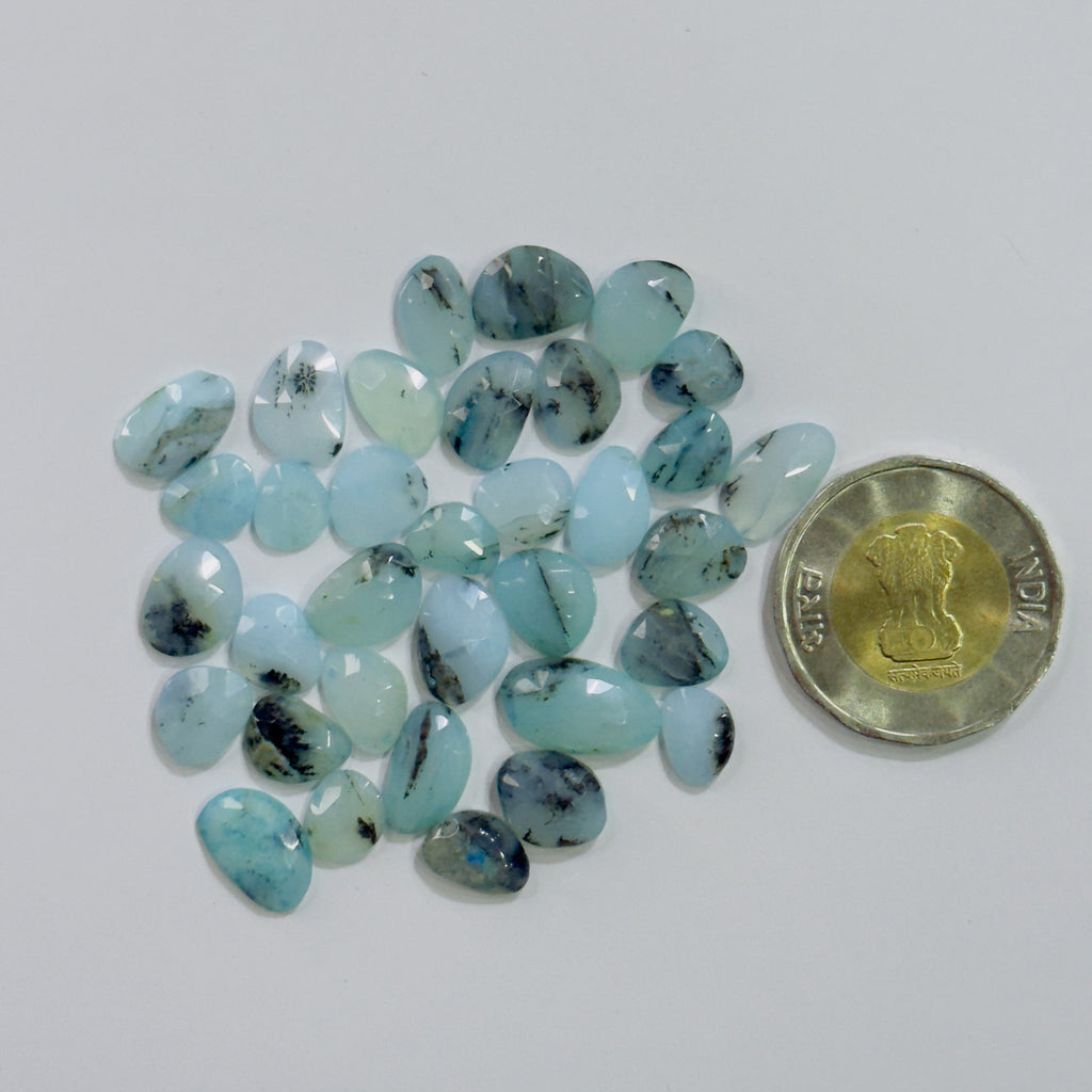 Turquoise stones with a coin for scale on a white background