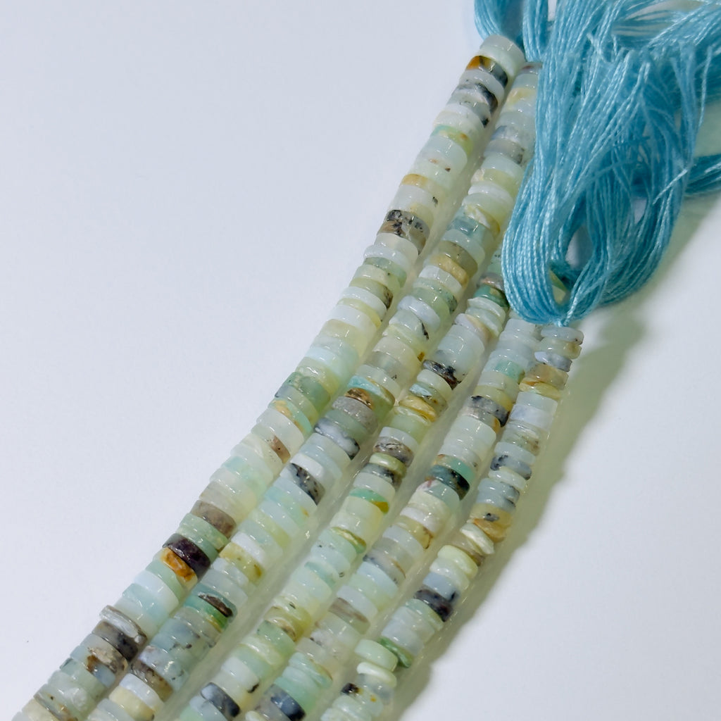 Beaded necklace with multicolored beads and a blue thread on a white background