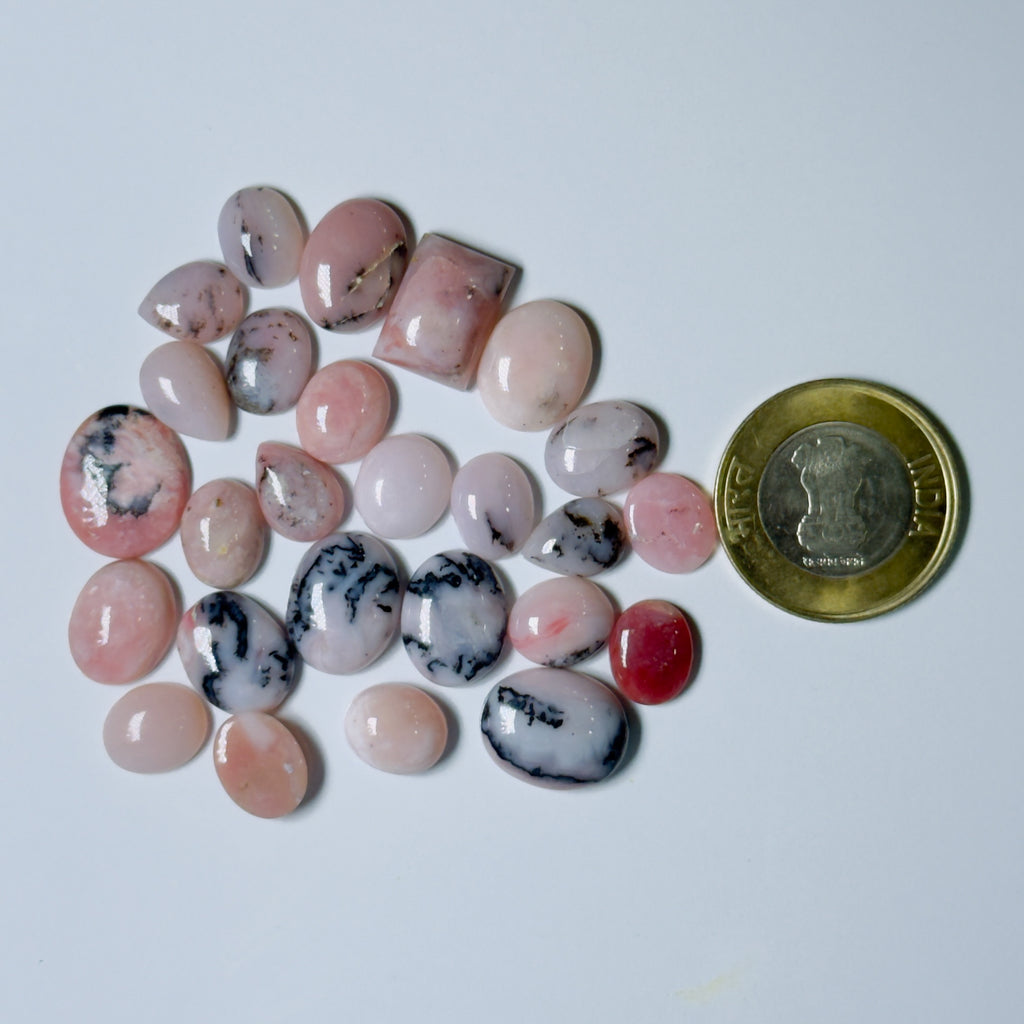 Collection of pink and black marbled stones with a coin for scale on a white background