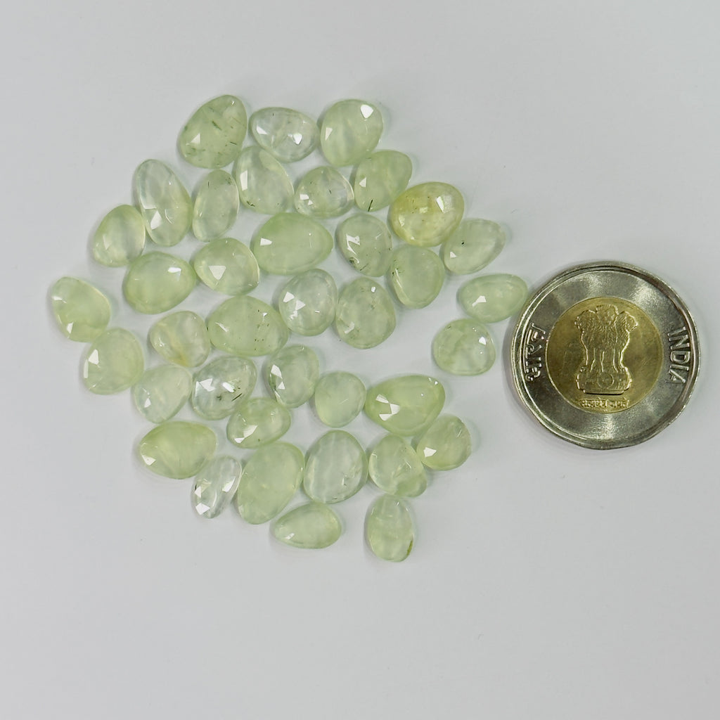 Green gemstones with a coin for scale on a gray background