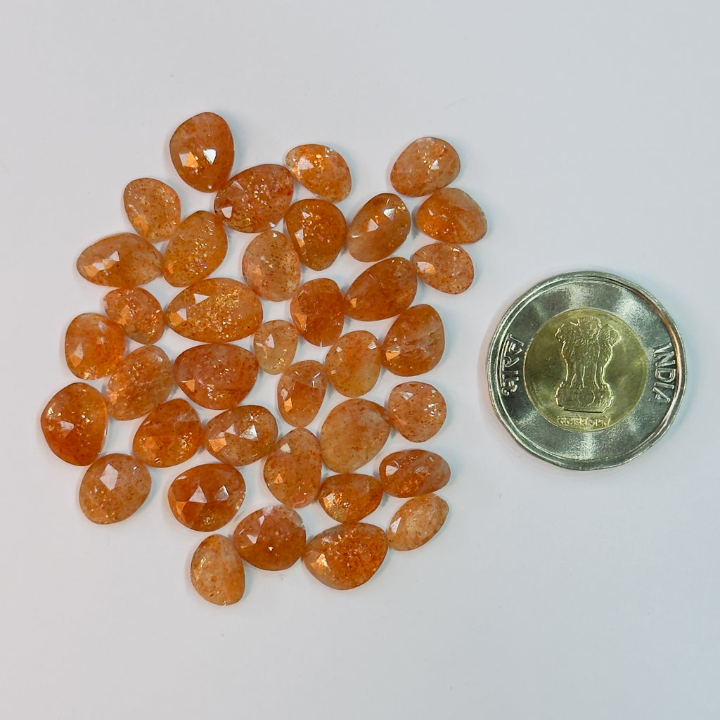 Orange gemstones with a coin for scale on a white background