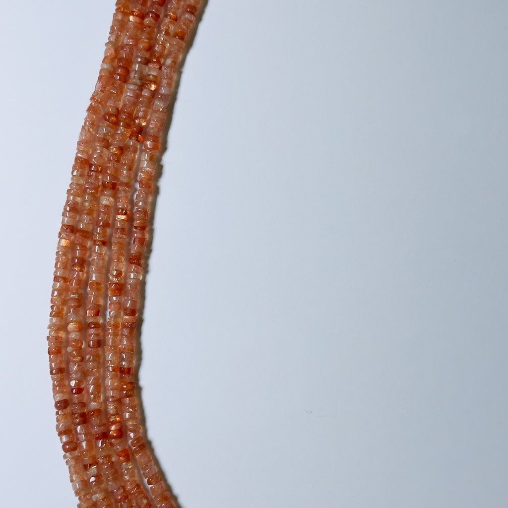 Close-up of a string of small orange beads on a light gray background