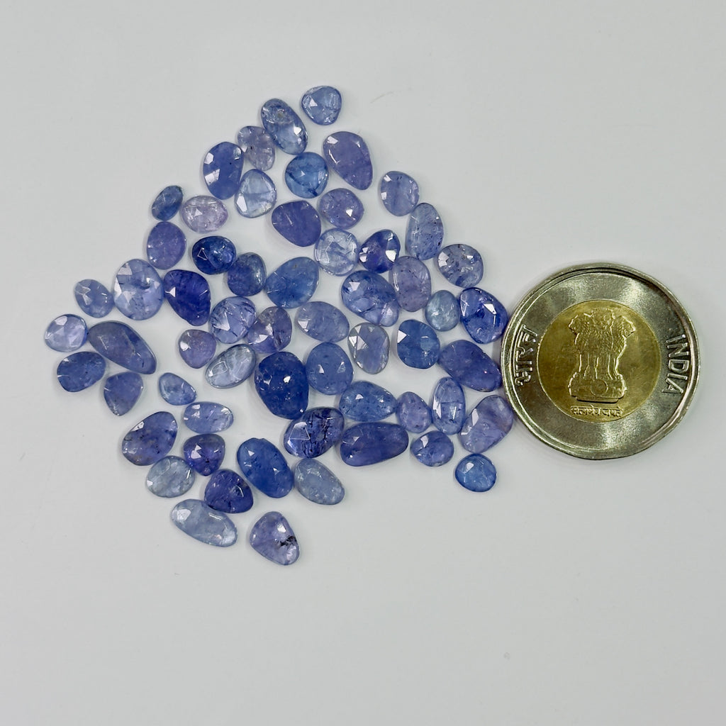 Blue gemstones with a coin for scale on a white background