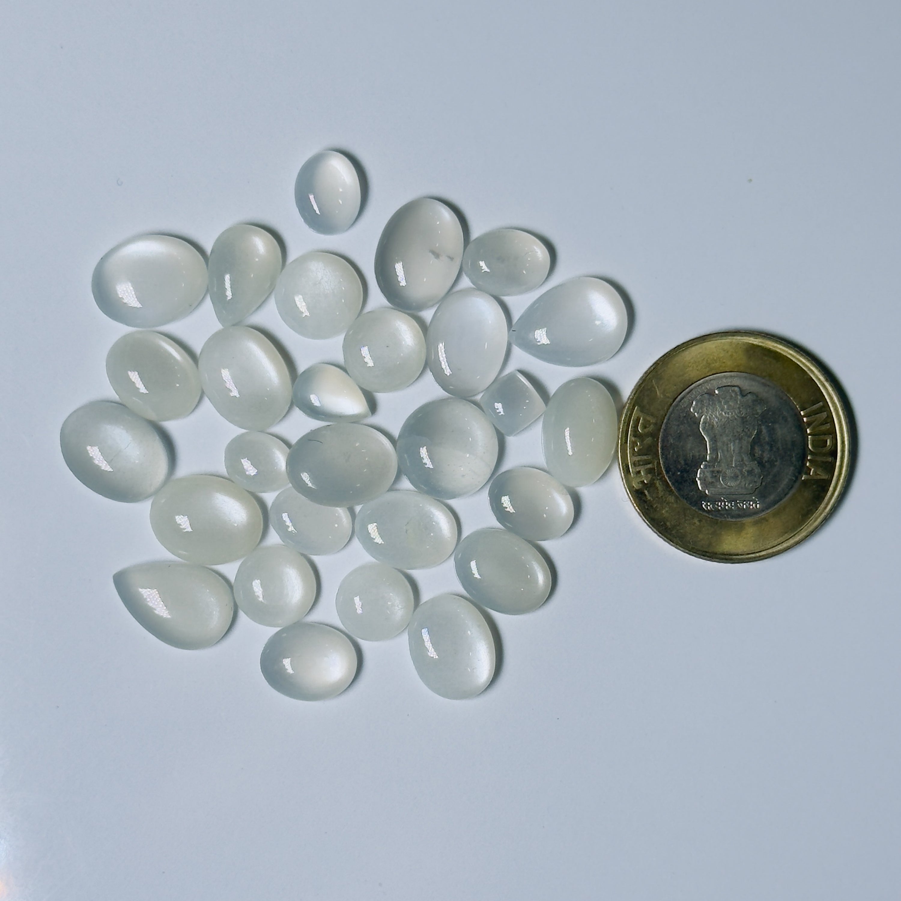 Teardrop-shaped White stones with a coin for scale on a White background