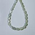 A beaded necklace made of smooth, rounded, light greenish-white stone beads arranged in a teardrop shape on a plain light gray background.