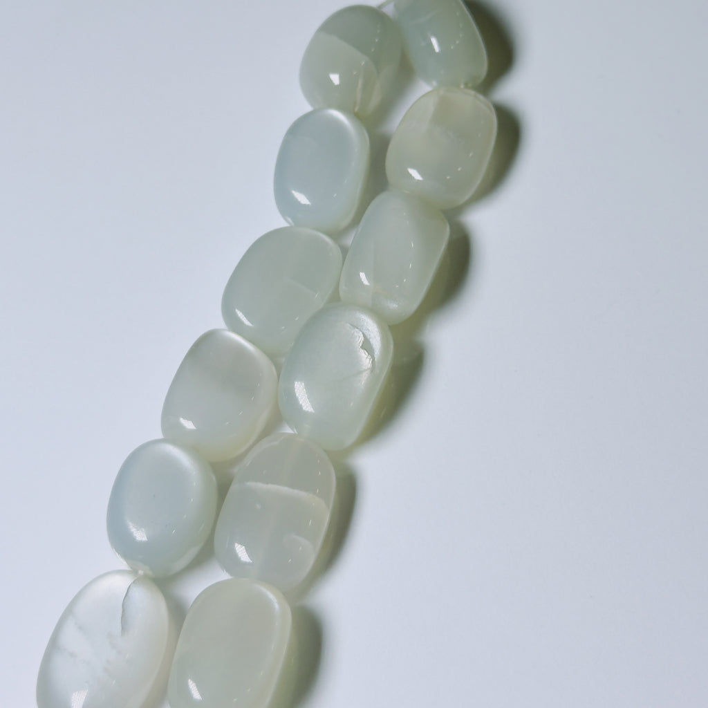 A strand of smooth, polished white stone beads with a milky, semi-translucent finish, arranged diagonally on a plain light gray background.