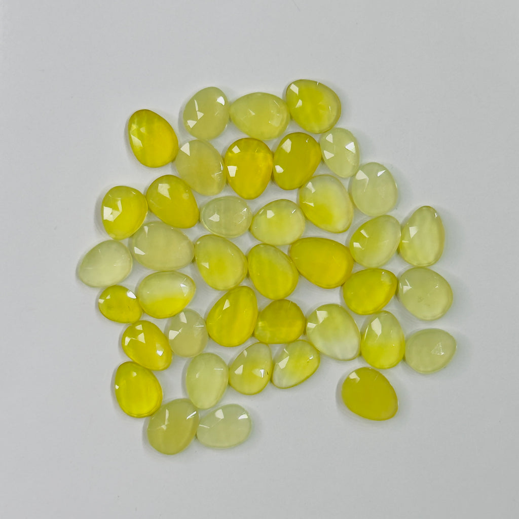 Collection of yellowish green gemstones on a light gray background