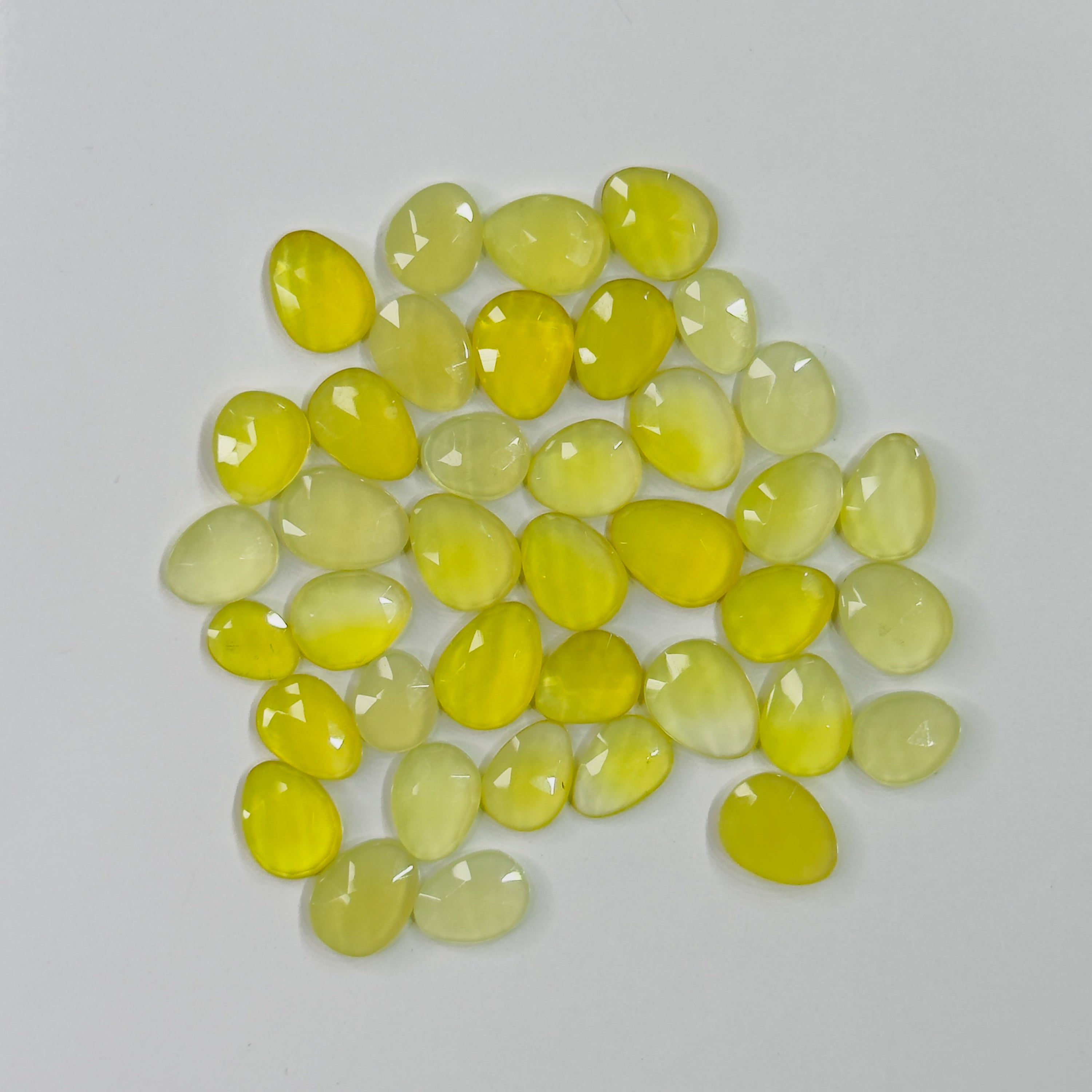 Collection of yellowish green gemstones on a light gray background